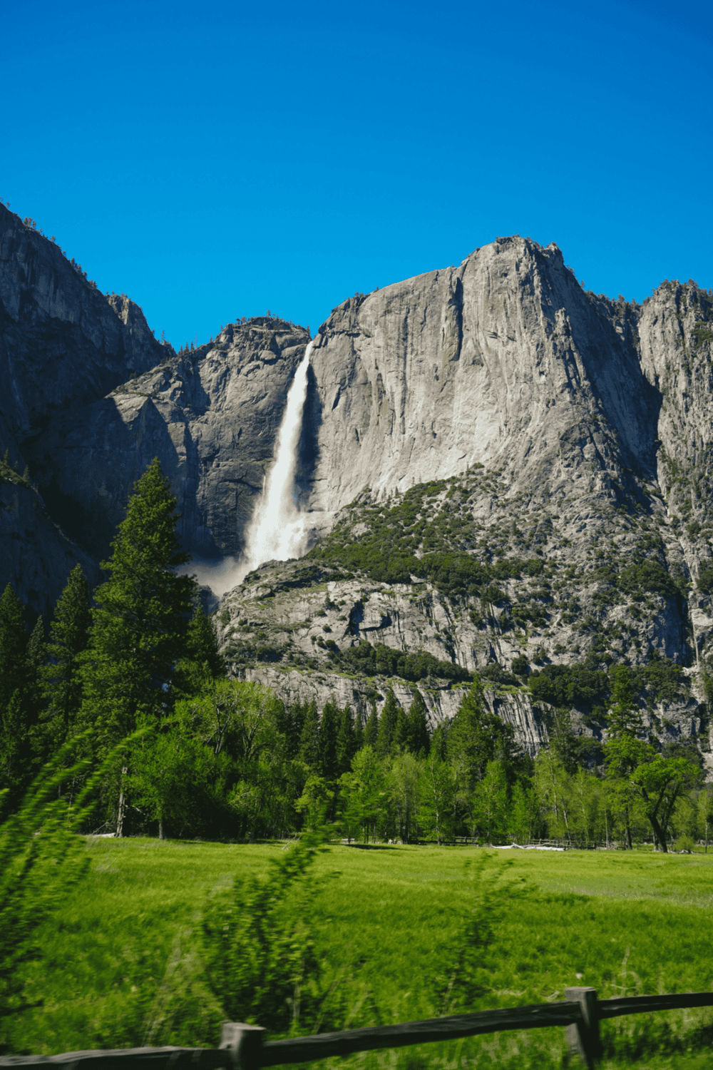 Majestic waterfall in Yosemite National Park with towering granite cliffs and lush greenery.