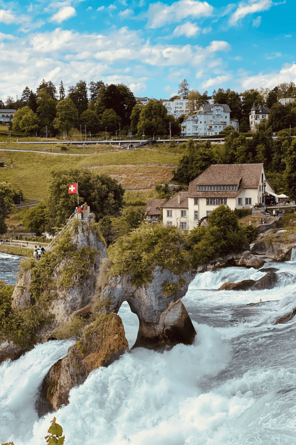Vibrant Swiss landscape showcasing the famous Rock of Love with a Swiss flag, river, and charming houses.