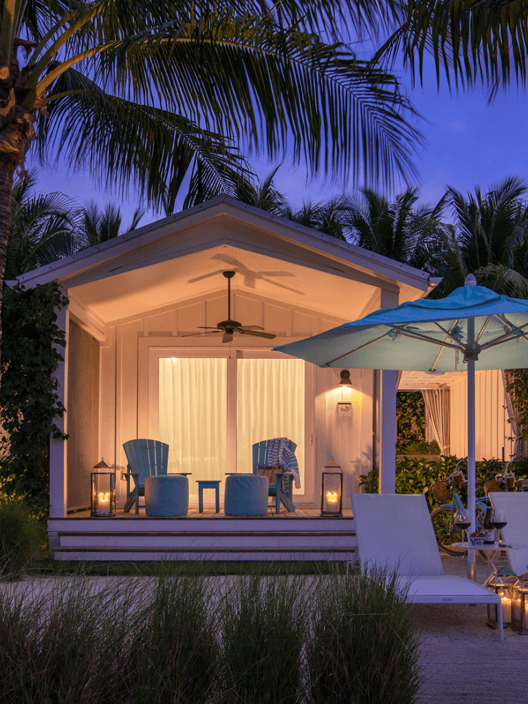 Relaxing tropical porch with cozy seating and palm trees at sunset.