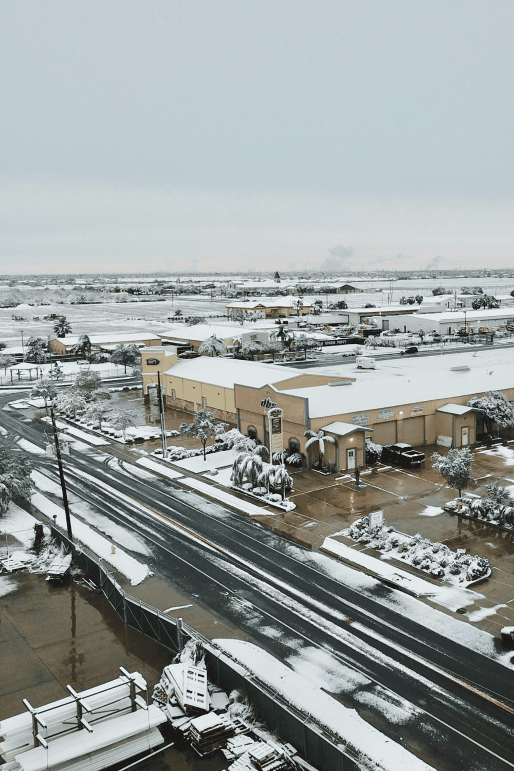 Snow-covered shopping center parking lot, QuestForDirections, outdoor retail space in winter, urban shopping district with snow, prepared for winter storms.
