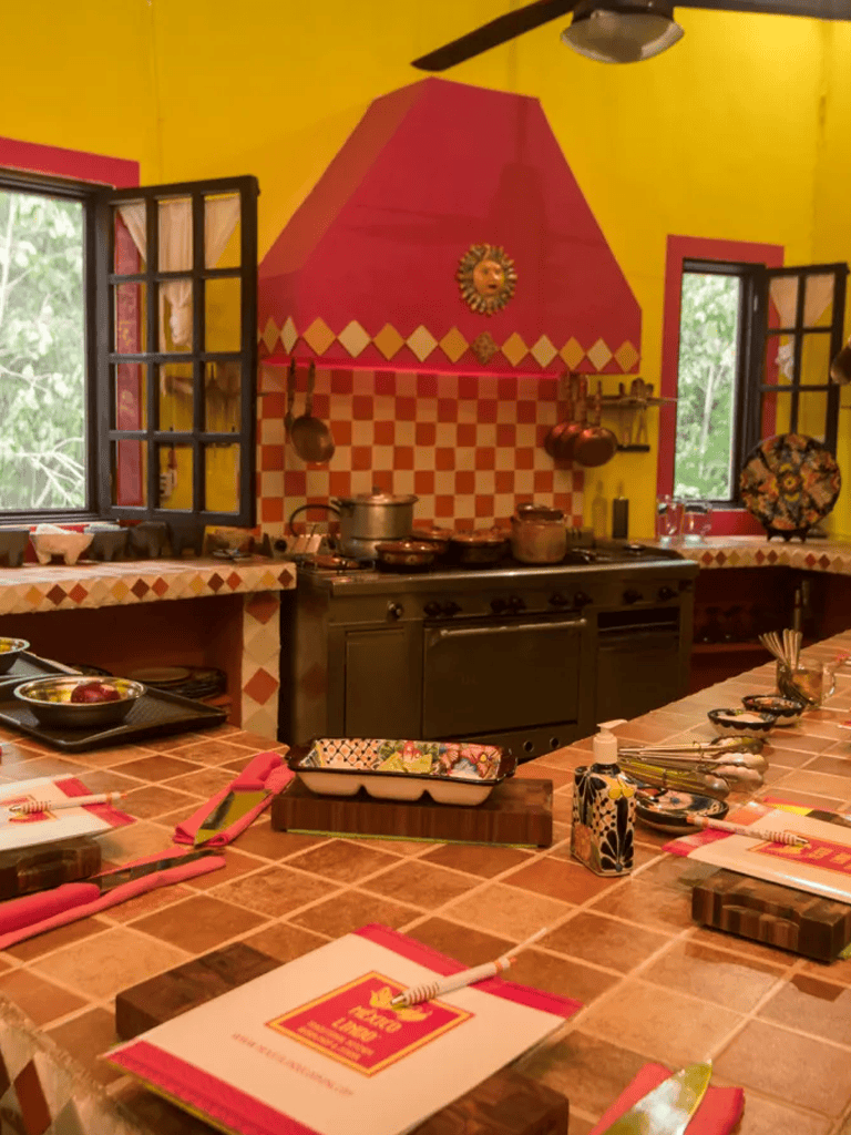 Colorful Mexican-inspired kitchen with vibrant yellow and pink walls, checkered backsplash, and rustic cooking utensils.