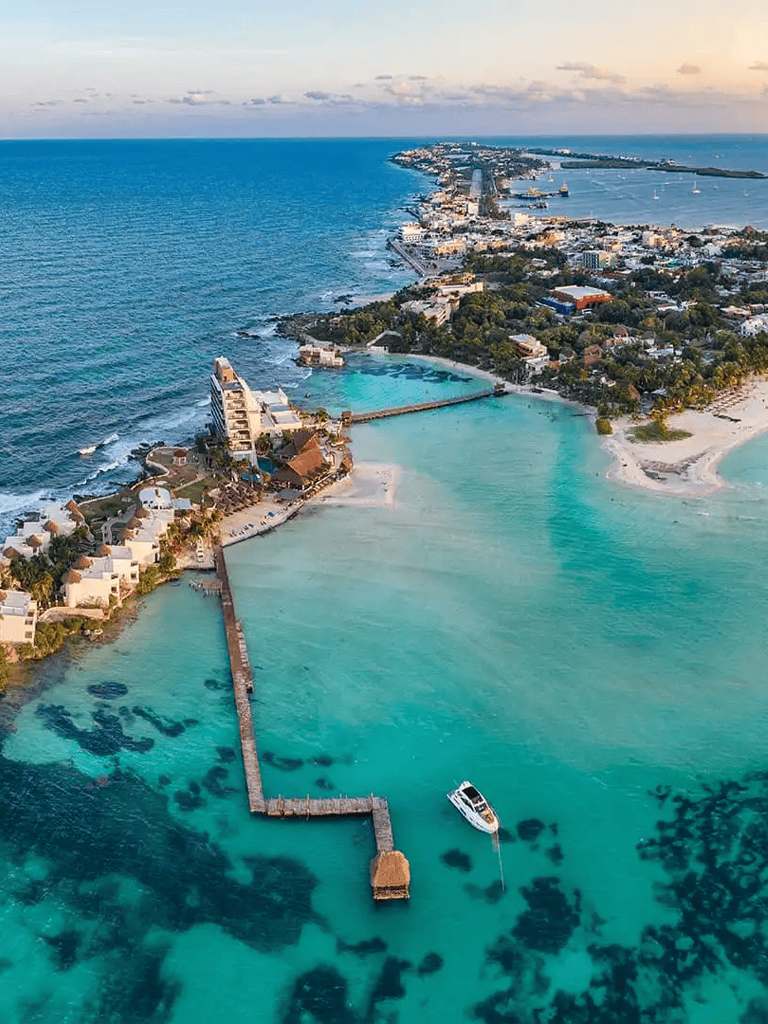 Aerial view of a coastal resort with turquoise waters, sandy beaches, and a harbor in a tropical destination.