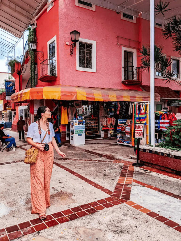 Colorful Mexican street scene with pink building and street vendor stalls.