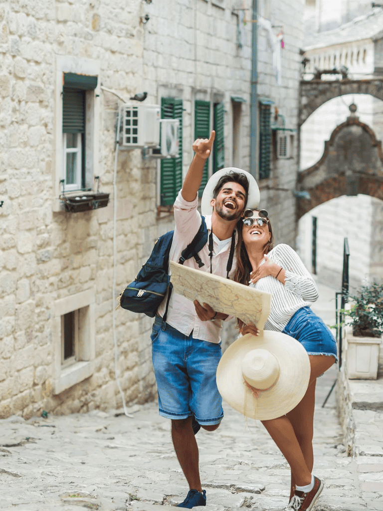Exploring picturesque historic alleyway with happy travelers holding a map and summer hat.