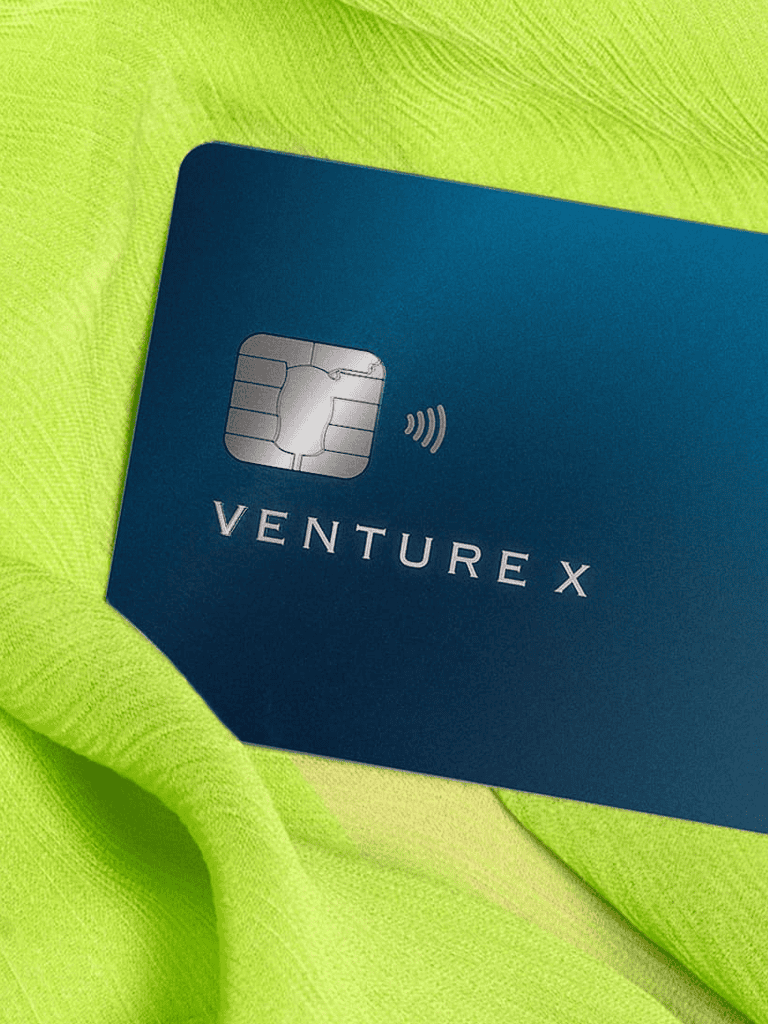 Secure VentureX credit card with contactless payment technology on bright green fabric.