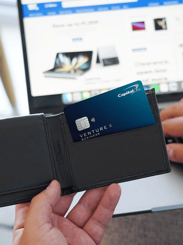 Credit card in wallet with laptop screen in background, emphasizing business and financial services.