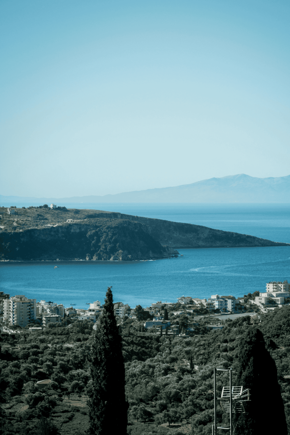 Panoramic view of coastline with mountains, ocean, and residential buildings, perfect for travel and navigation.