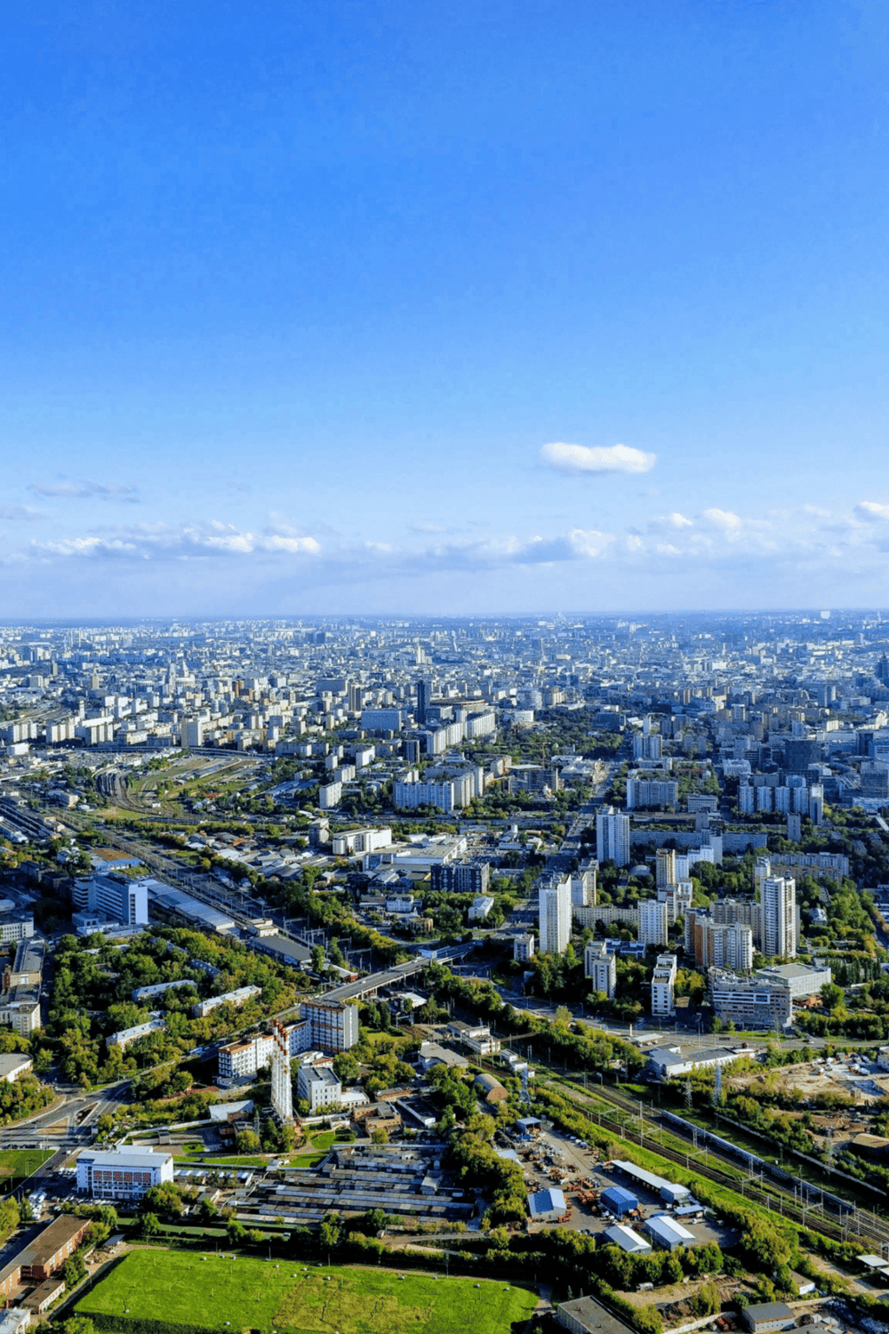 Aerial view of a bustling cityscape with high-rise buildings and green parks on a clear day.