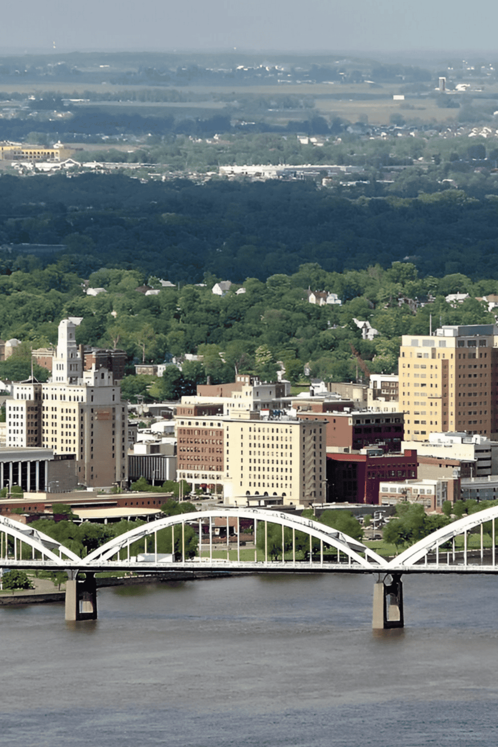 Overlooking a city skyline with buildings, a bridge, and lush green parks in the background.
