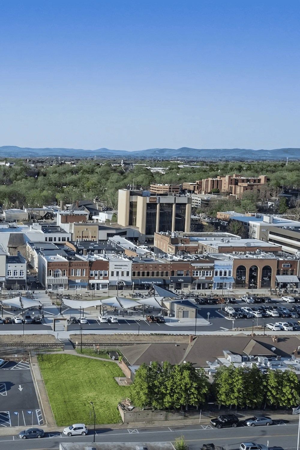 Modern cityscape with shops, parking, and surrounding greenery, located in a scenic mountainous area.