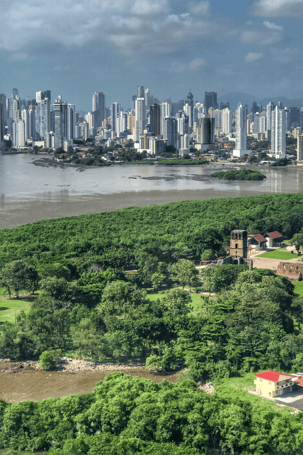 0. Modern city skyline with lush green park and river in foreground, Panama City, Panama.
