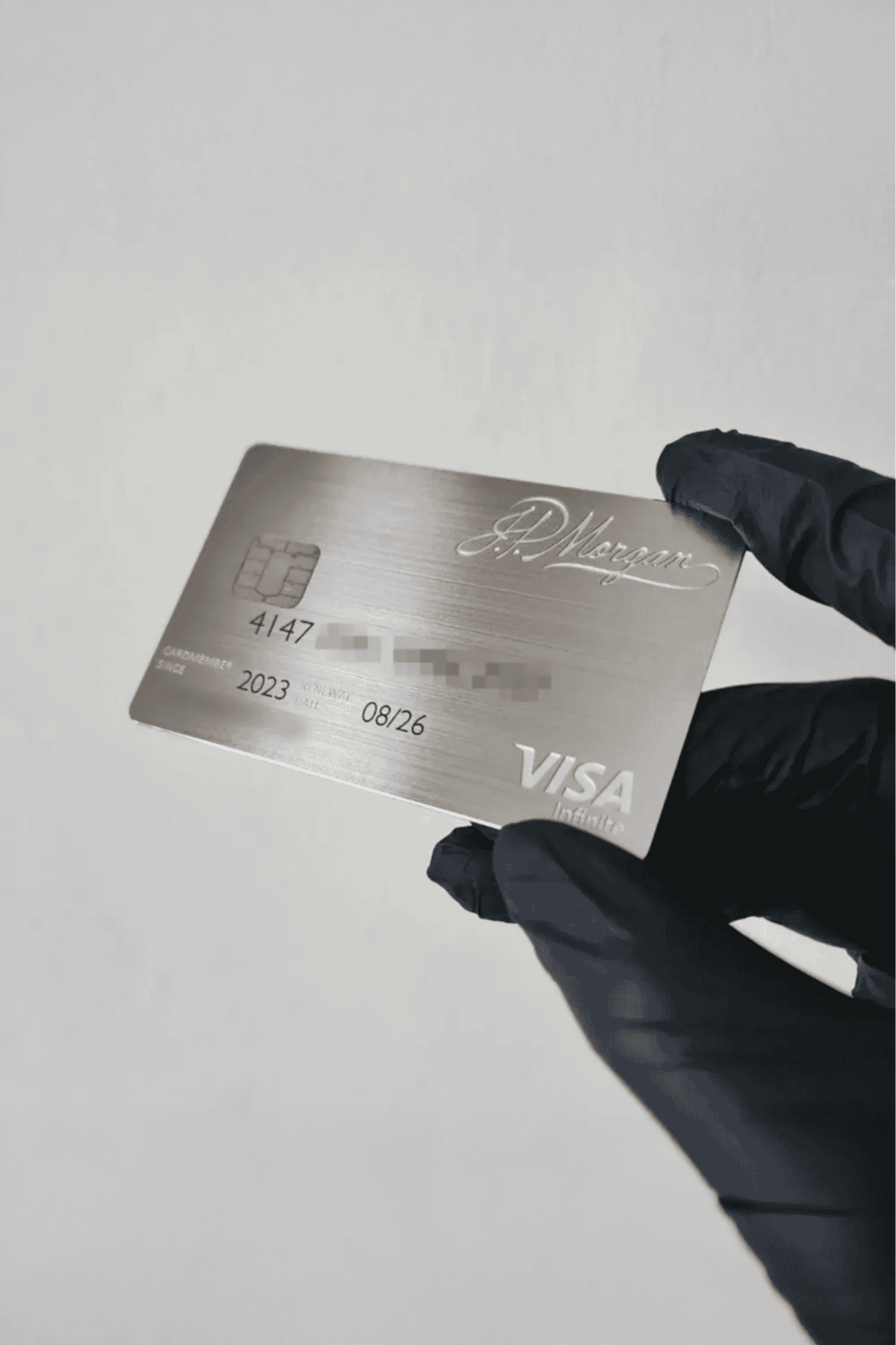1. Elegant silver Visa card held by gloved hand for secure online shopping and travel.