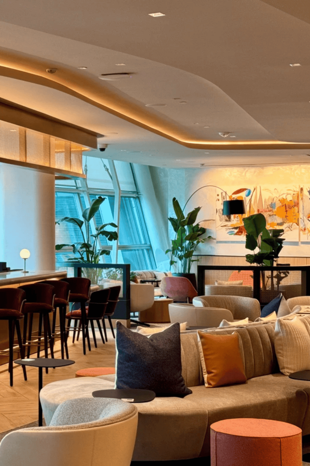 Modern hotel lounge with vibrant interior, cozy seating, and lush indoor plants for a welcoming atmosphere.