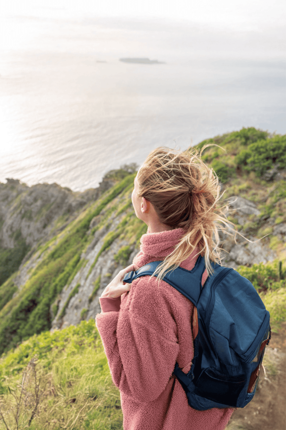 Seaside hiking woman with backpack overlooking ocean scenery, adventure travel, nature exploration, outdoor activity, explore coastlines.