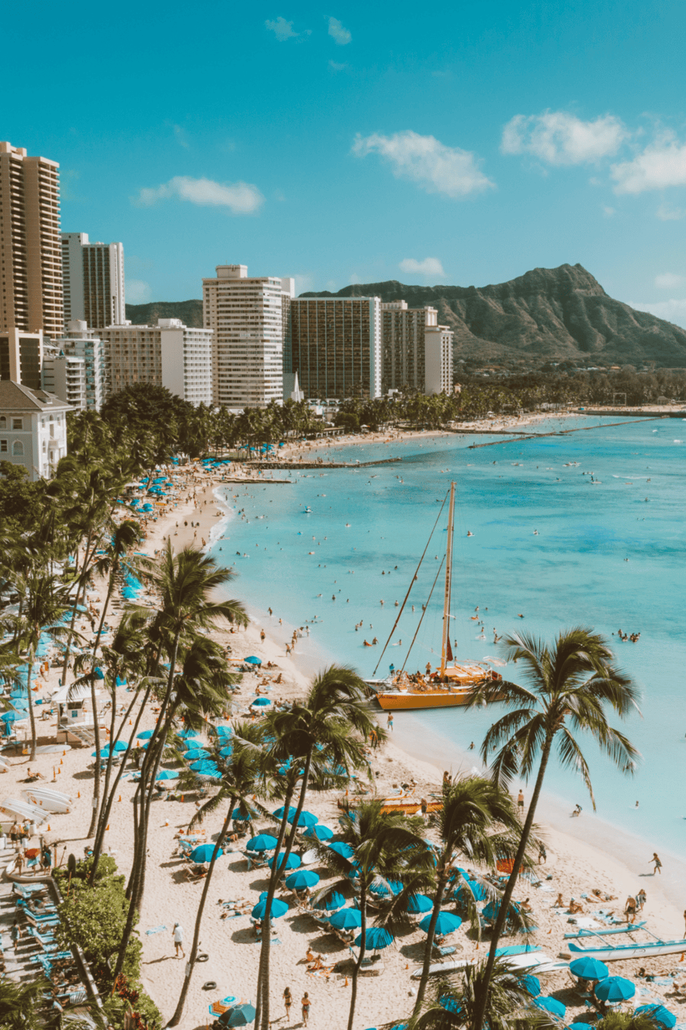 Beachfront Honolulu skyline with palm trees and sailing boat, Hawaii travel destination.