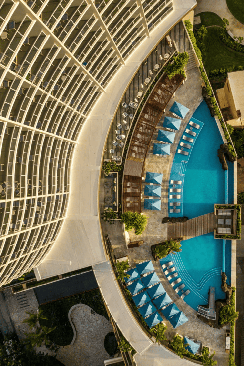 Bright hotel pool with cabanas and lounge chairs in a modern high-rise building.