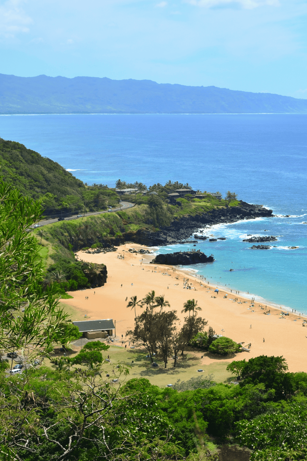 Spectacular Hawaiian coastline with lush greenery, sandy beach, and ocean views, perfect for sightseeing and outdoor adventures.