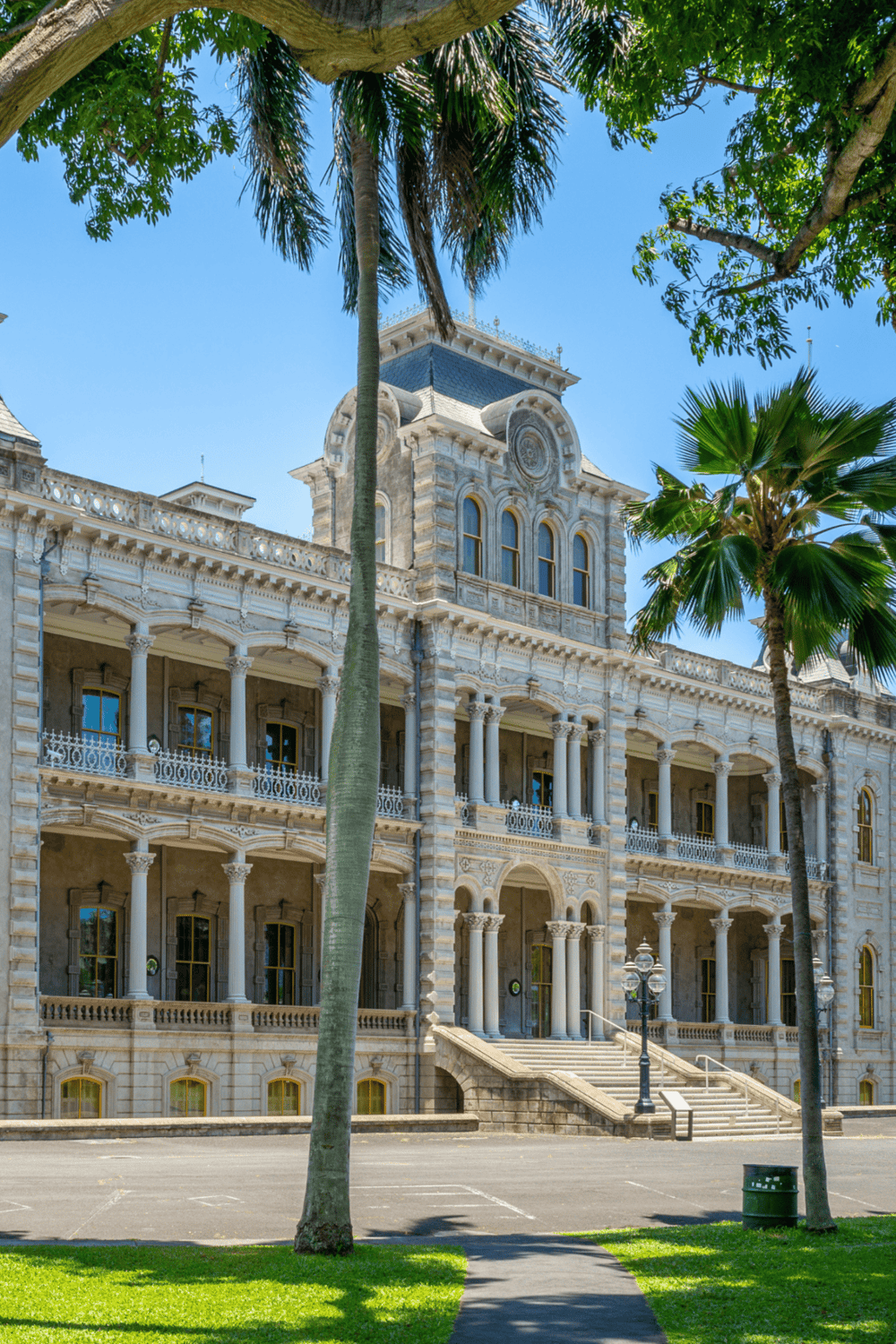 Elegant historic courthouse with ornate architecture and lush palm trees in a scenic park setting.