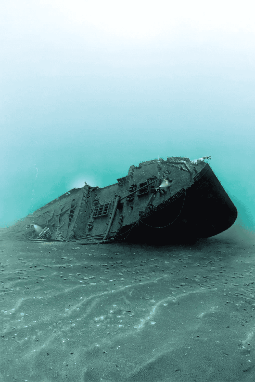 Wreckage of sunken ship on ocean floor under clear water.
