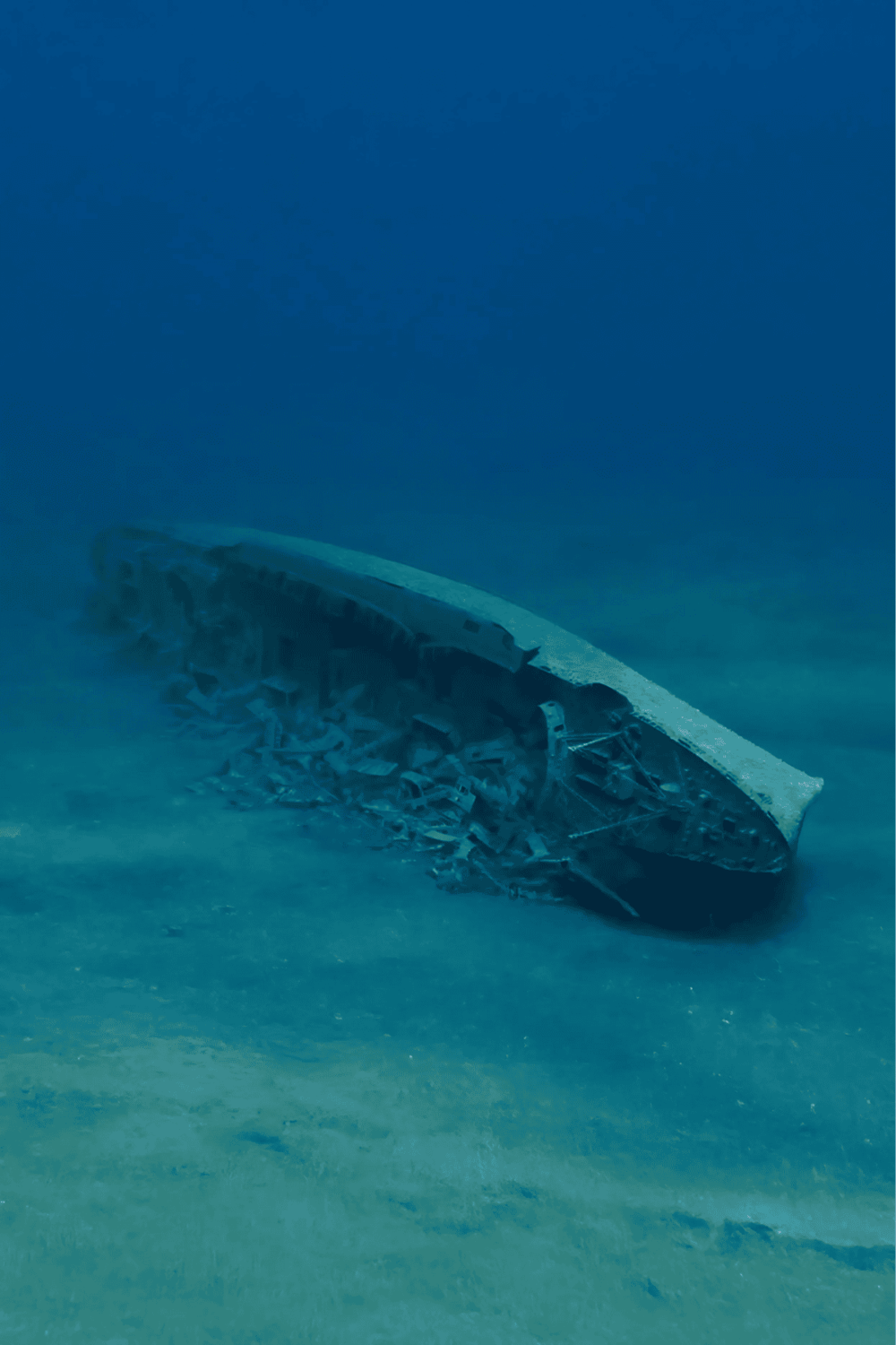 Destroyed submarine wreck submerged underwater with marine environment.