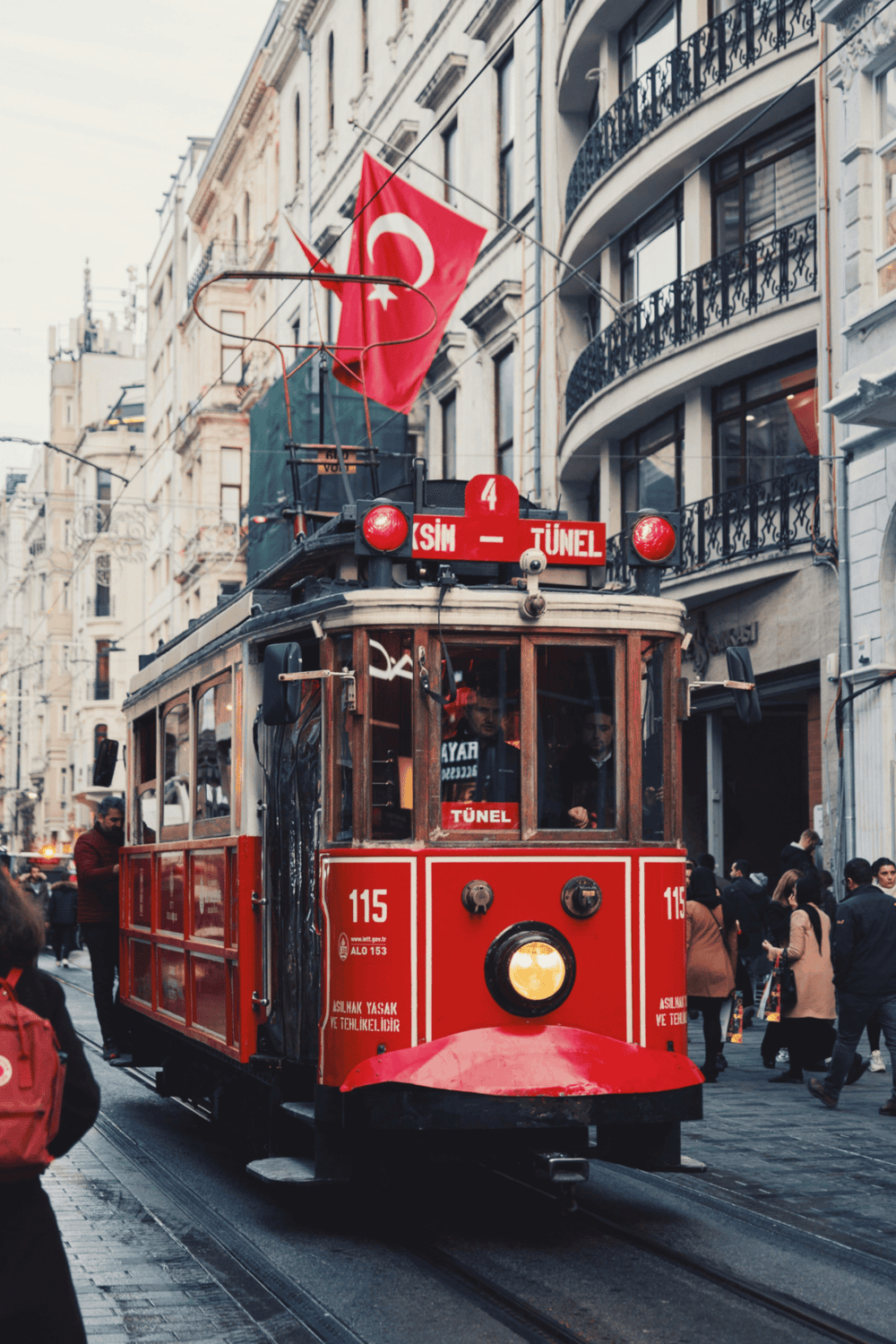 Vintage tram in Istanbul with Turkish flags, bustling city streets, and historic architecture.