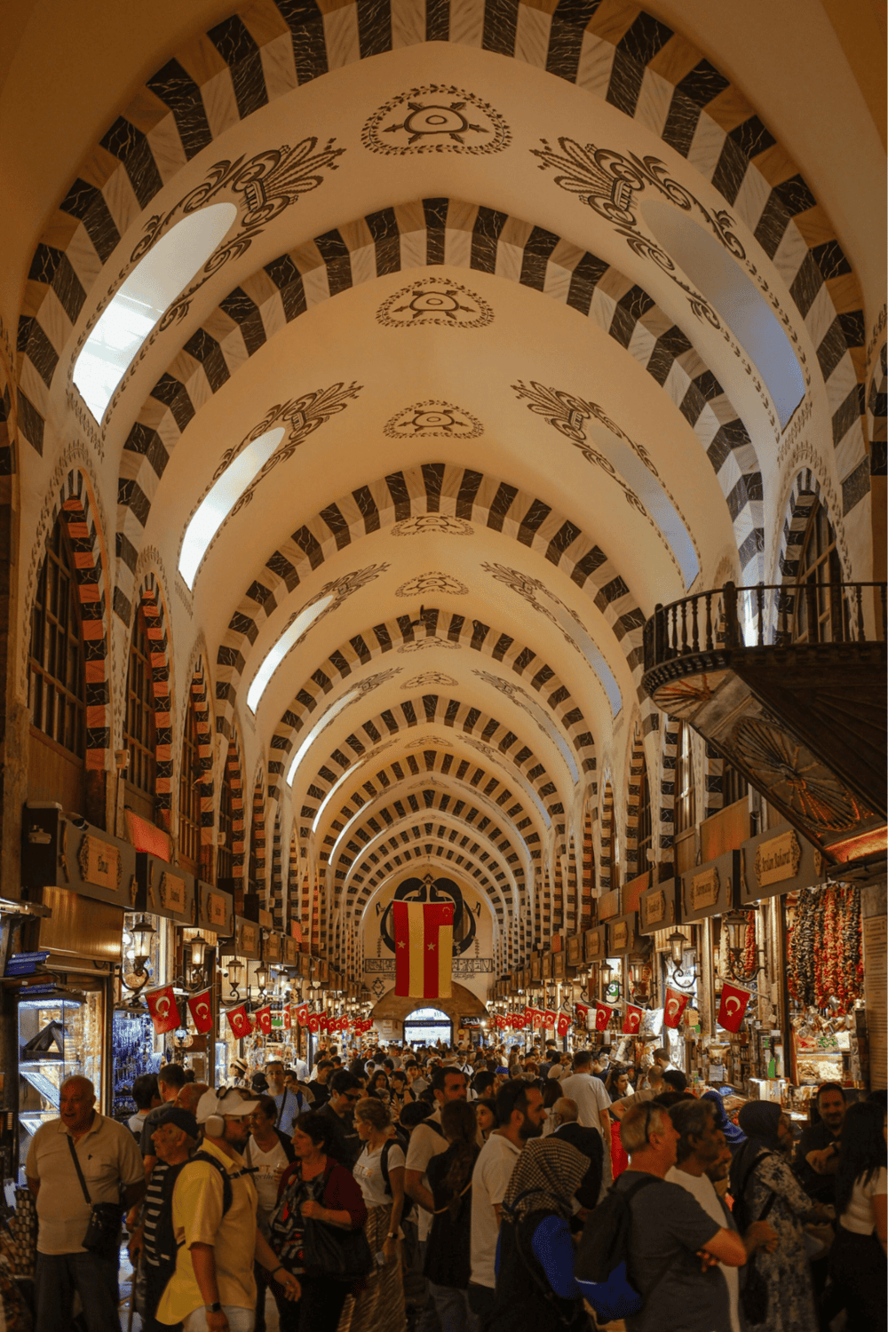 1. Vibrant indoor market in Turkey with Turkish flags, historic architecture, diverse vendors, and bustling crowds.