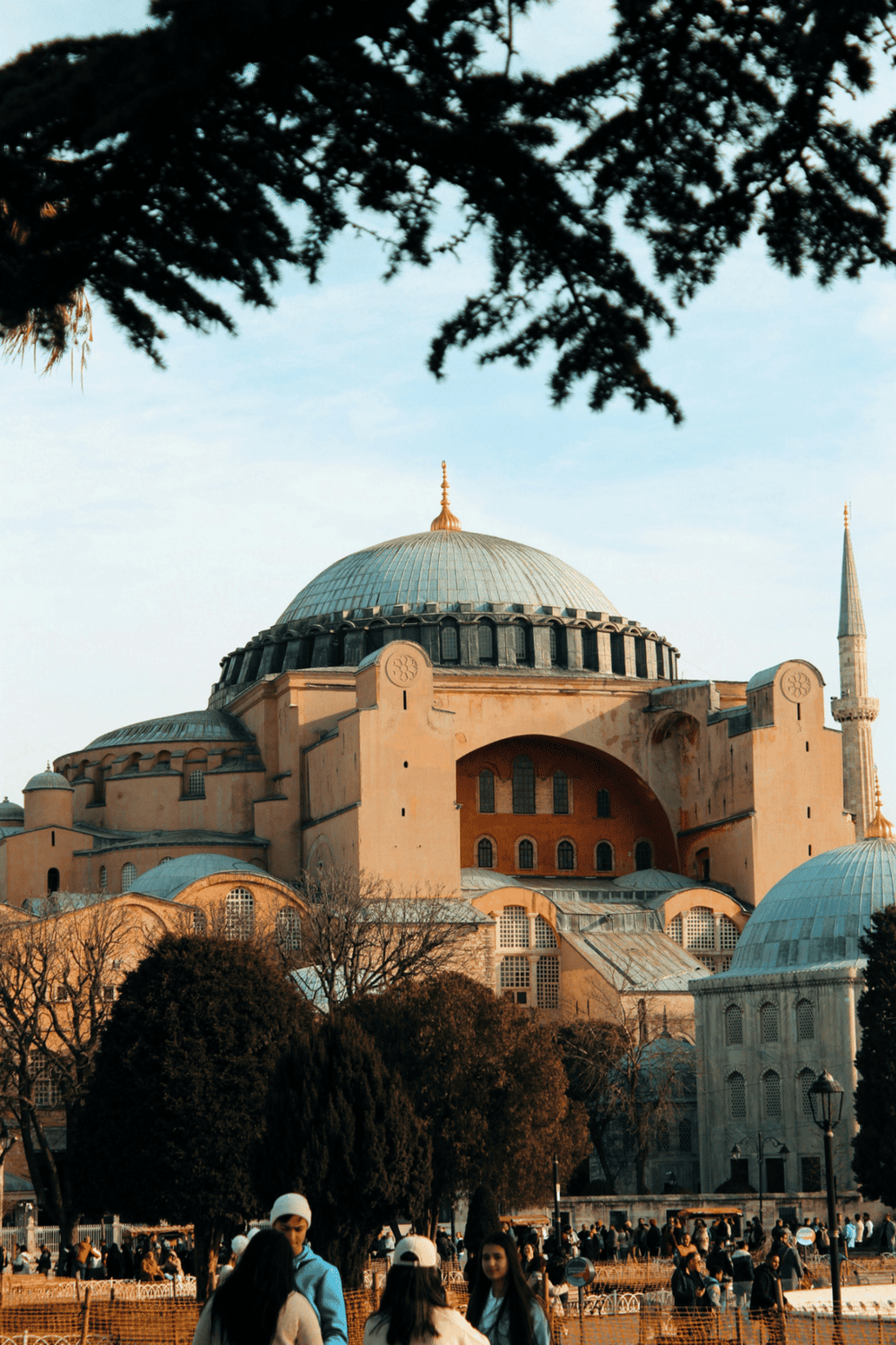 Majestic Hagia Sophia Mosque in Istanbul, Turkey, with historic architecture & visitors exploring outside.