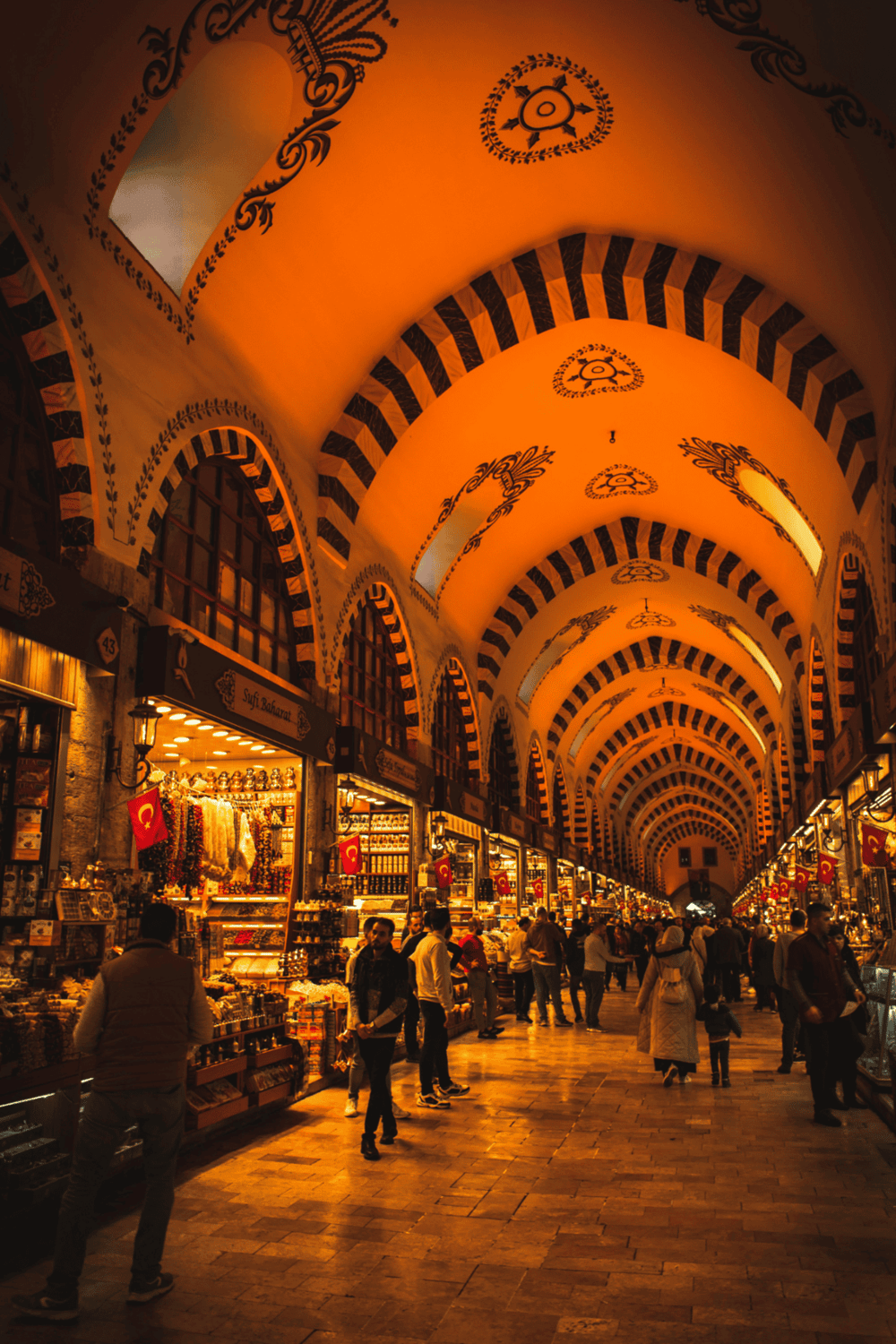Bright indoor marketplace with Turkish flags, vibrant shops, and intricate ceiling designs.