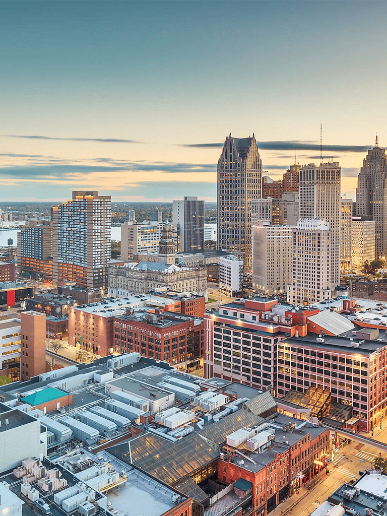Aerial view of Detroit skyline with tall skyscrapers and cityscape at sunset, showcasing urban development and architecture.