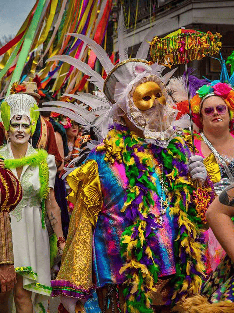 Brightly dressed parade participants in colorful costumes, masks, and decorations at a lively, festive event.