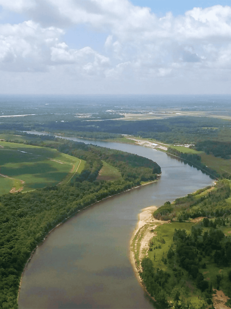 Serene river landscape with lush greenery and blue skies, ideal for nature and outdoor adventure enthusiasts.