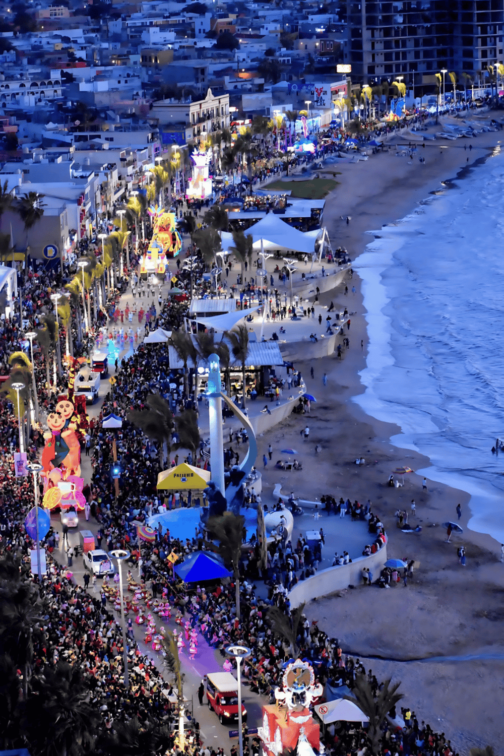 Crowded beach boardwalk with vibrant attractions and night lights in Cancun, Mexico.