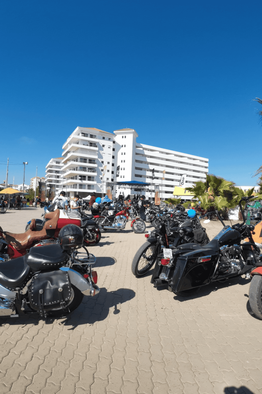 Vintage motorcycle parking lot near beach resort, sunny day, white building background, tropical vacation vibe, QuestForDirections.