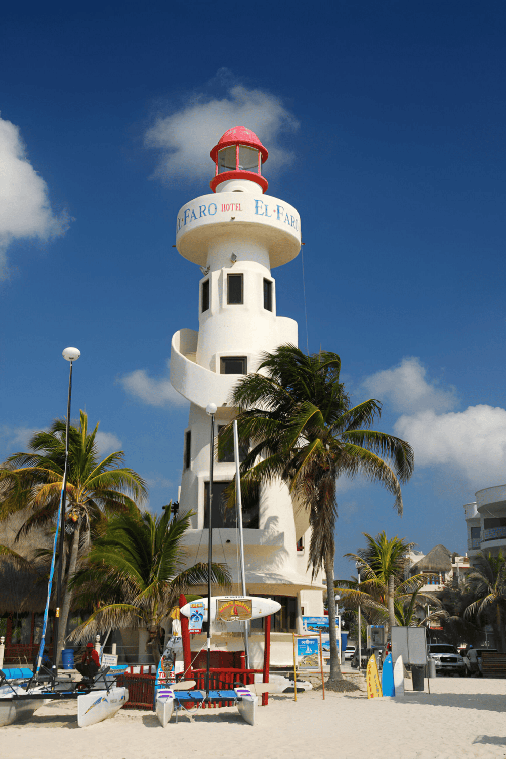 Lighthouse at Cancun with palm trees and blue sky, iconic travel landmark.