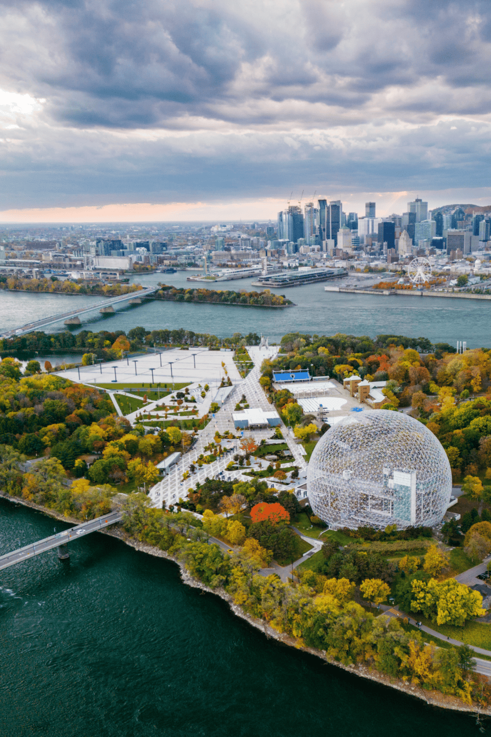 Aerial view of Quest for Directions park with downtown skyline, river, and iconic geodesic dome, connecting urban exploration and outdoor activities.
