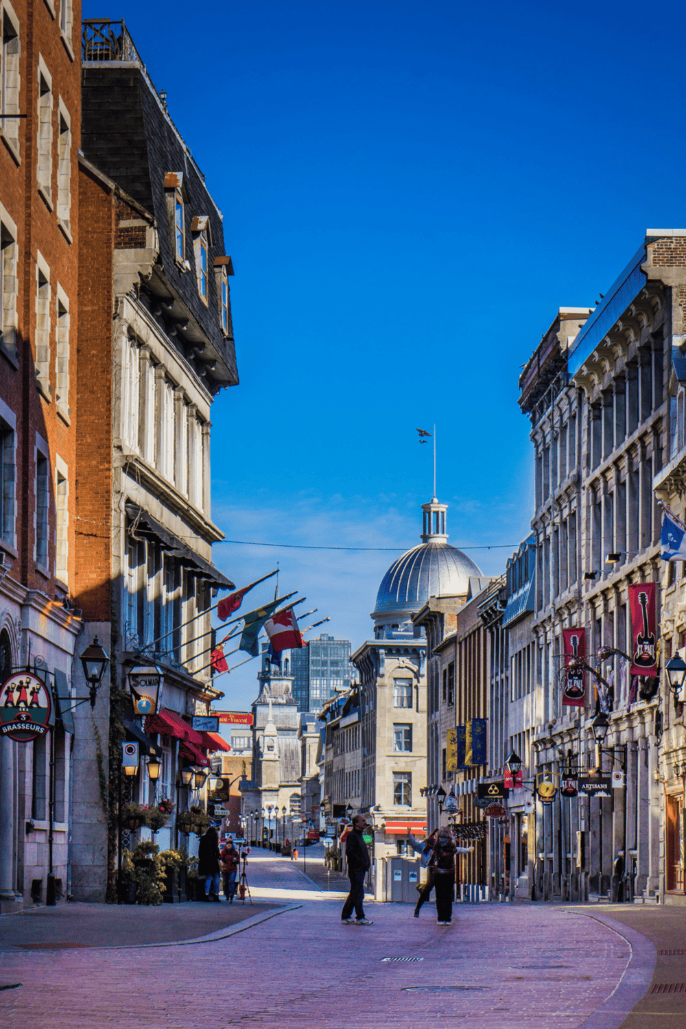 Historic Montreal Old Town street with flags and shops, vibrant cityscape and iconic architecture.