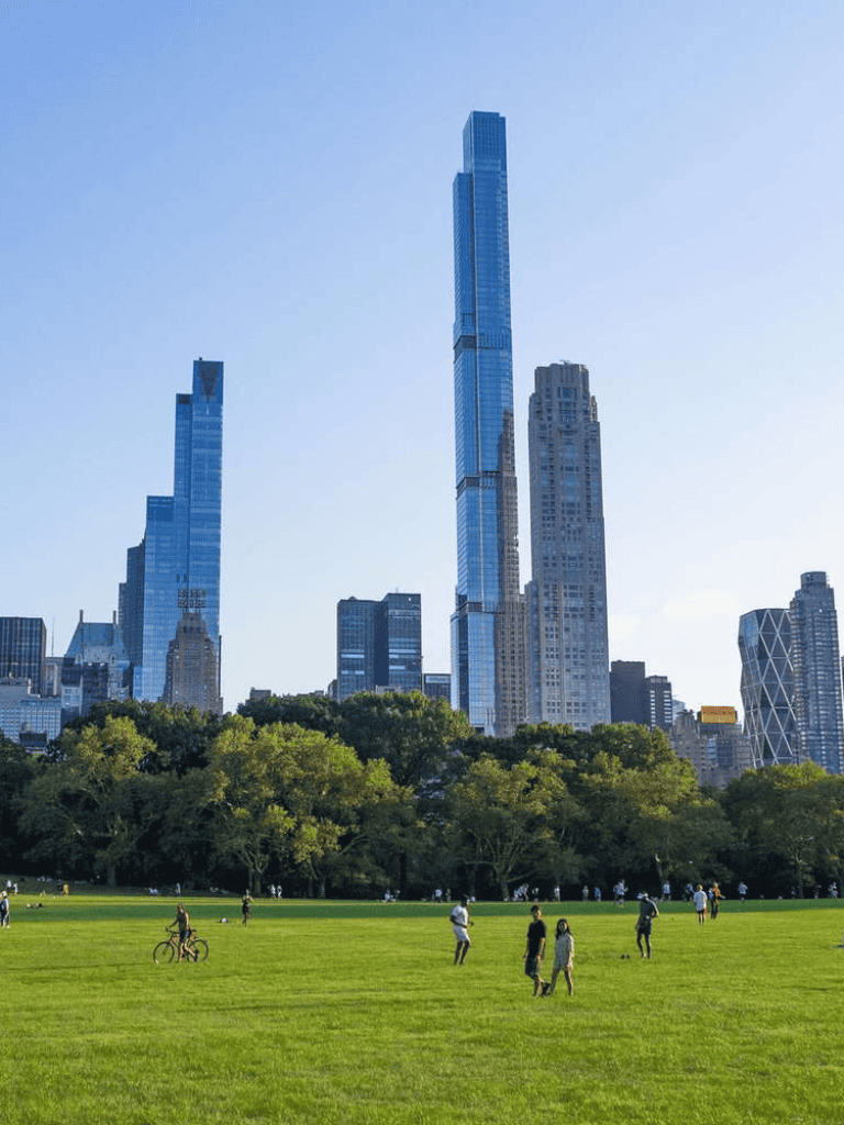 Tall skyscrapers in New York City with Central Park in the foreground, showcasing urban skyline and city park landscape.