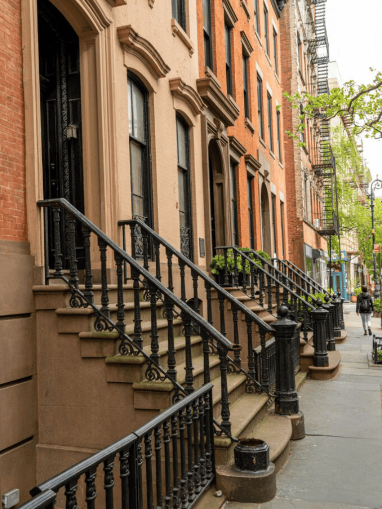 Historic brownstone building with stoop stairs and ornate black iron railings in an urban neighborhood.