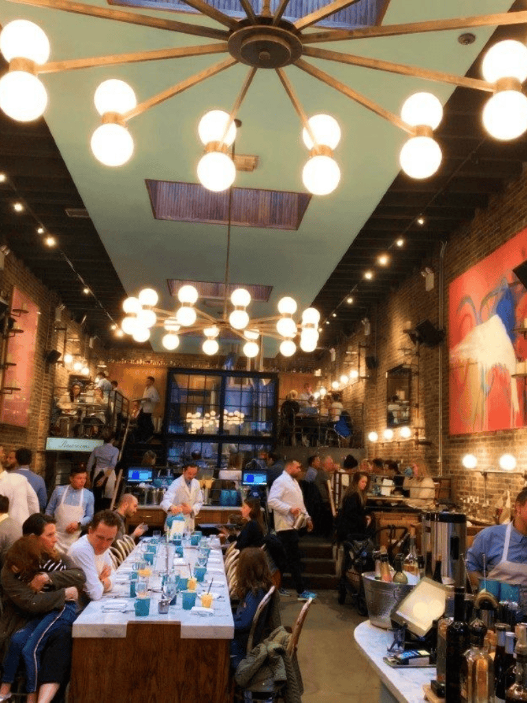 Elegant restaurant interior with high ceiling, modern chandelier, and brick walls at QuestForDirections.