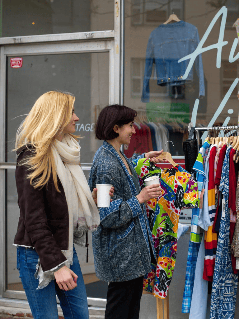 Women shopping vintage clothing outside storefront for sustainable fashion and eco-friendly wardrobe choices.
