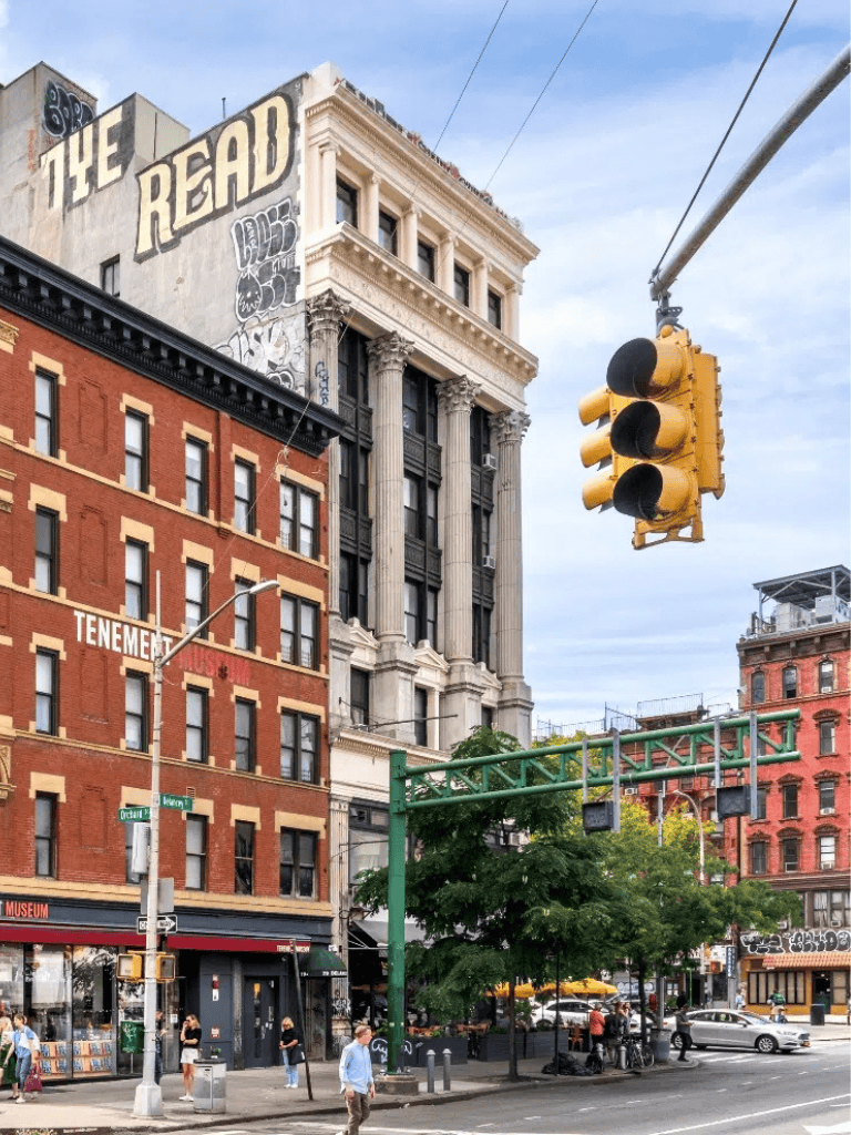 Downtown city street with historic buildings, traffic lights, and pedestrians in an urban setting.