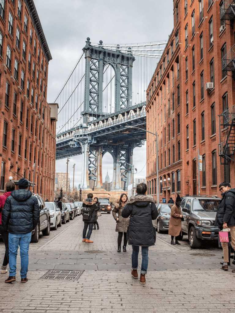 Broadway Bridge Brooklyn seen from Dumbo streets in NYC, urban scene with pedestrians and city architecture.