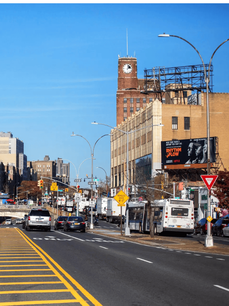 Downtown city street with traffic, buildings, and a clock tower, representing urban navigation and directions.