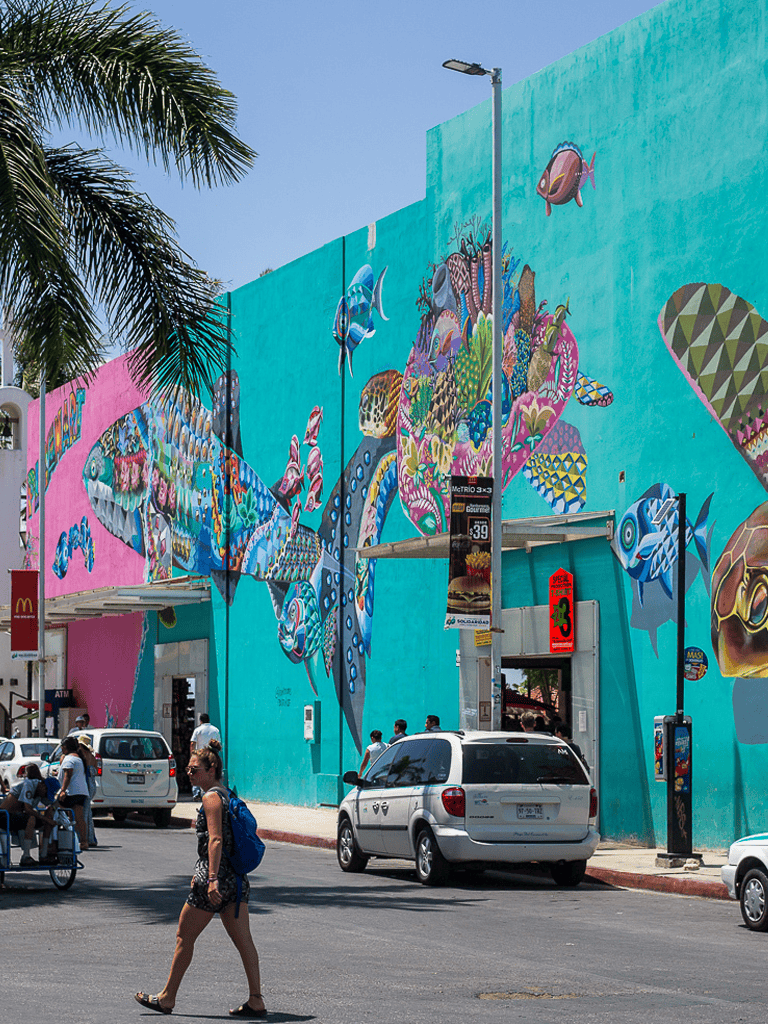 Bright urban mural of colorful fish and underwater scene on city building wall.
