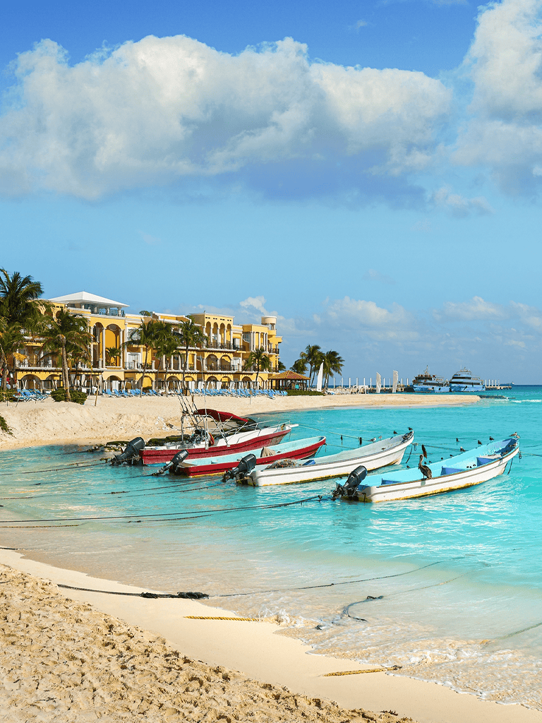 Luxurious beach resort with boats on turquoise waters, palm trees, and ocean view for vacation planning.