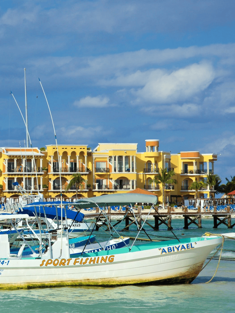 Colorful beachside boats with yellow resort buildings in the background, promoting travel and vacation destinations.