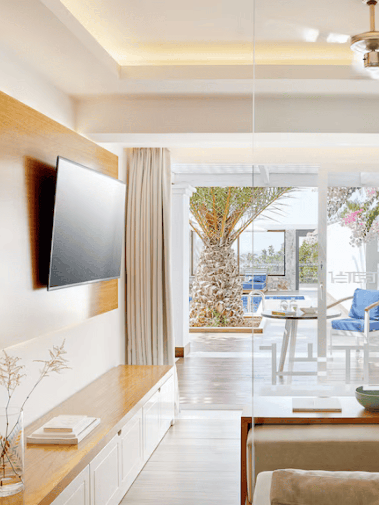 Bright coastal living room with view of palm trees and outdoor seating, modern design, natural light, QuestForDirections.