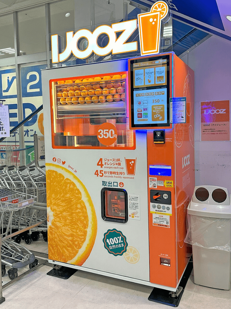 Fresh orange juice vending machine at QuestForDirections in a shopping mall.