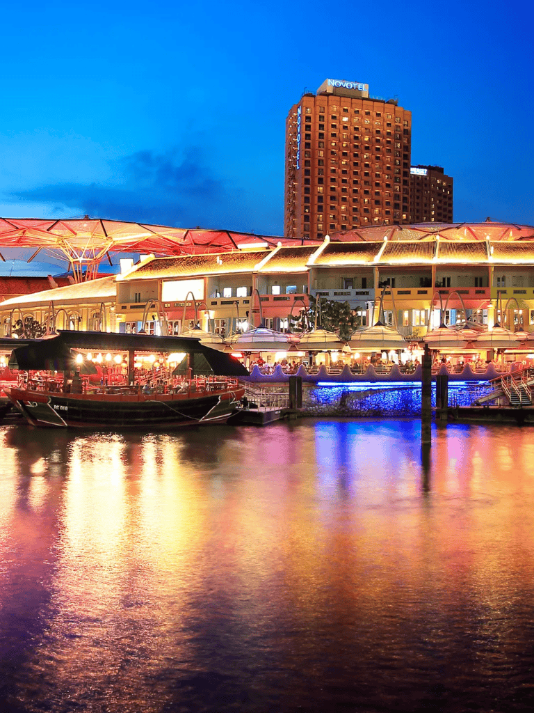 Vibrant night view of Quest for Directions waterfront with illuminated buildings and boats on the river.