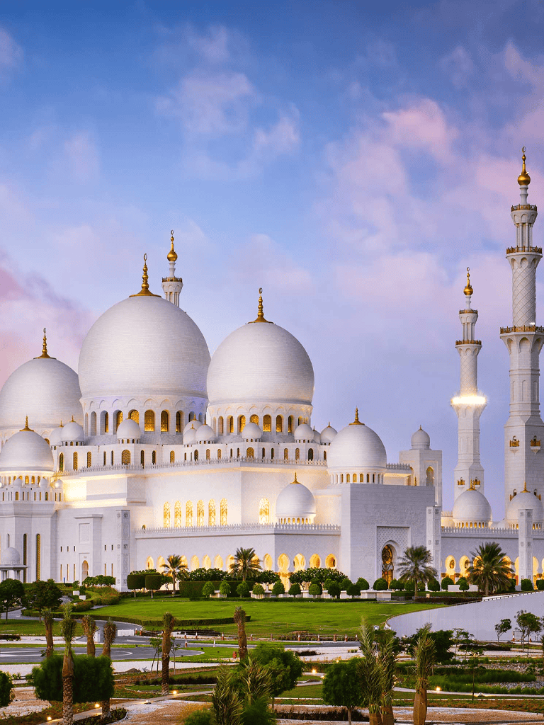 Elegant white mosque with domes and minarets, Dubai tourism landmark, scenic view at sunset.